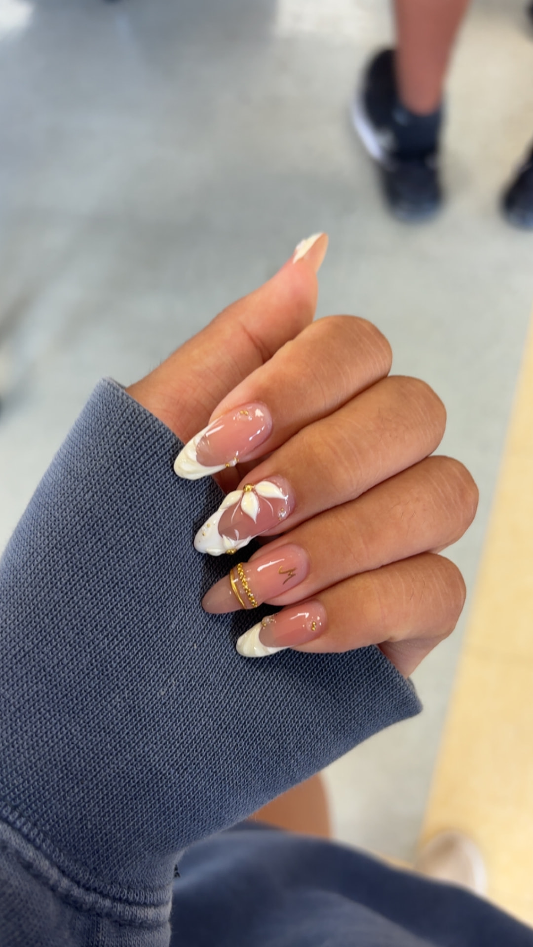 Glossy almond nails with ivory French tips, floral art, and gold details by Kulia